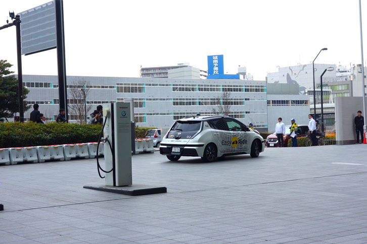 多くの記者に見守られる中、日産グローバル本社を出て行く実験車両。運転席にはステアリングから両手を放したスタッフが乗車していた。