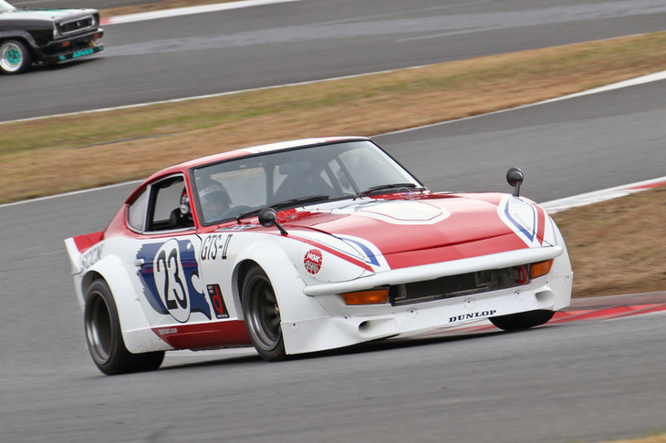 JCCA（日本クラシックカー協会）主催のクラシックカーレースに参戦している日産車を中心とするNISSANヒストリックカーエキシビションレースで、フォーメーションラップを先導した1973年「フェアレディ240ZG」。ターンフローだった生産型のL型エンジンに対し、クロスフロー化されたLY型2.9リッターエンジンを積んだテストカーで、ドライバーはもちろん「Zの柳田」ことレジェンドドライバーの柳田春人。