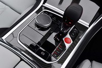 「M」のエンボス加工が施されたシフトレバー。周辺にはインフォテインメントシステムの操作デバイスや走行モードのセレクターが並ぶ。