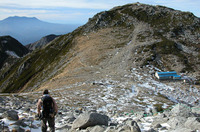 中岳の頂を越え、眼下に小屋が見えた。さあ、あれが今晩の宿だ、と思いきや……。向こう側にかすんで見えるのは御嶽山。