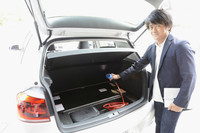 充電用のプラグを持つ筆者。バッテリーは荷室フロア、後席下、およびセンタートンネル内に分散して搭載される。荷室は実用的な容量（238リッター）を残している。