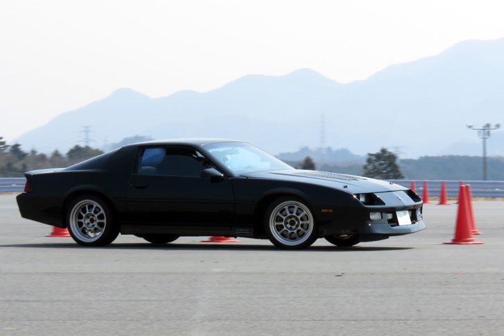 8の字走行のコースを走る“サードカマロ”こと3代目「シボレー・カマロ」。昔はなんてことない普通のスポーツカーだったのに、今やすっかり“佳（よ）き時代のアメ車”である。うーん。カッコイイな。