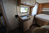 室内に入って、左側にはキッチンとベッドルームがレイアウトされる。キッチンには、3つのバナーレンジと、水切り台、まな板としても使えるプレート付きのステンレスシンクが備わり、レンジの下には、104リッターの冷凍冷蔵庫が標準装備される。