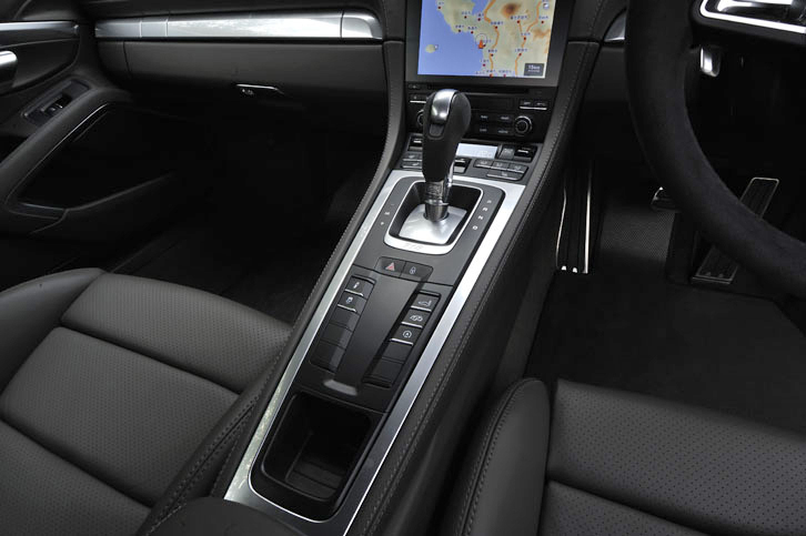 後方に向かってなだらかに傾斜したセンターコンソール。シフトレバーの手前には、サスペンションの設定ボタンやリアウイングの調節スイッチが並ぶ。