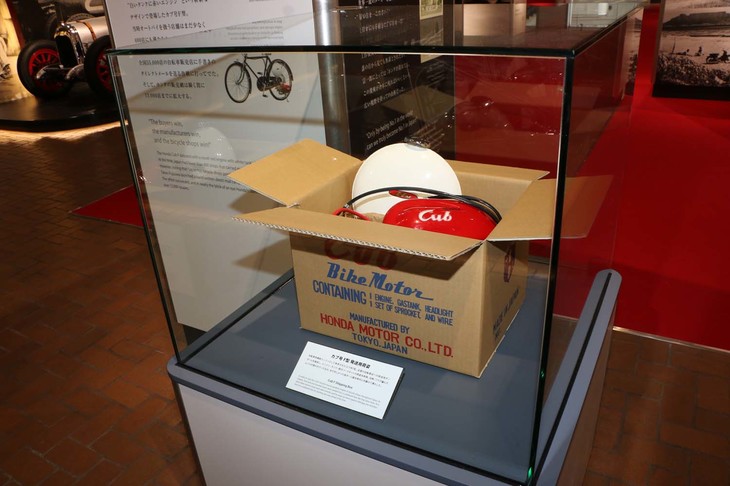 自転車補助エンジンとして発売された「カブ号 F型」の梱包（こんぽう）を再現したもの。当時まだ珍しかった専用段ボール箱の中に、エンジン、燃料タンク、取り付けパーツセットが収められ、全国の自転車店に出荷された。