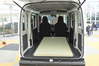 一畳のたたみが積まれた「e-ハイゼット カーゴ」の荷室。荷室長×荷室幅×荷室高＝1920×1410×1250mm（2人乗車時）という寸法をはじめ、荷室のスペックはエンジン車と共通。ユースフルナットはeアクスルを搭載する都合で一部が省略されたが、それでもe-ハイゼット カーゴで30カ所（2人乗り仕様は47カ所）、「e-アトレー」で16カ所も設けられている。