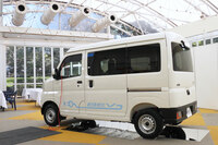 屋内に展示された「e-ハイゼット カーゴ」。写真は外部給電のデモの様子で、フロントドアウィンドウに「外部給電アタッチメント」をはさむことで、ドアや窓を閉じた状態でも、車内のアクセサリーコンセントから電気を取り出すことができる。