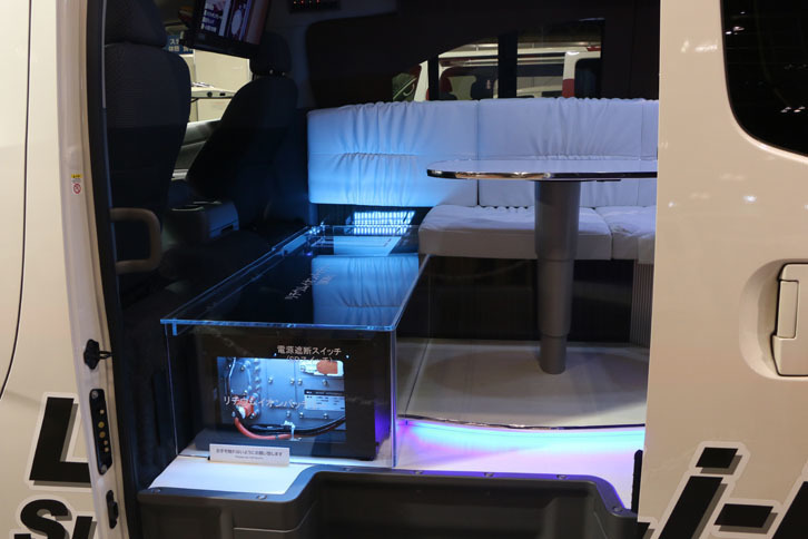 運転席／助手席の背後に8kWhのリチウムイオンバッテリーを搭載。出先でエアコンや電子レンジ、テレビなどの電化製品が使用できるのが売り。