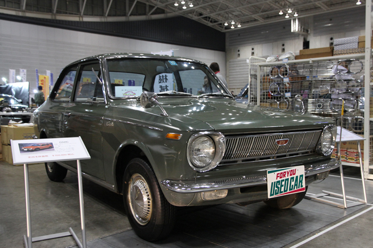 1967年「トヨタ・カローラ1100デラックス」。非常に珍しいダイアナオリーブという色名の塗装、アイボリーの内装も含め、ほぼ未再生という初代カローラの初期型。フルハートの出展で、価格は75万円。