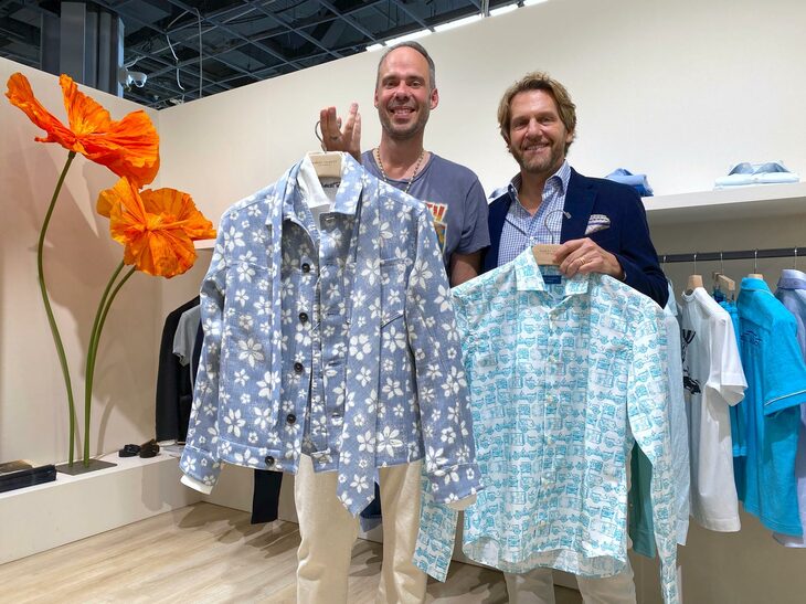 州花カリフォルニアポピー柄のシャツを掲げているのはロバート・タルボットのクリエイティブディレクター、セバスティアン・ドーリンガー氏（左）。「ウィリス・ジープ」柄のシャツを持つのはアレックス・アンジェルシックCEO（右）。