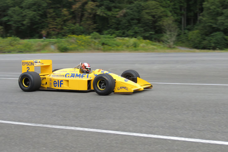 「ロータス ホンダ100T」の黄色いボディーが山の緑に映える。