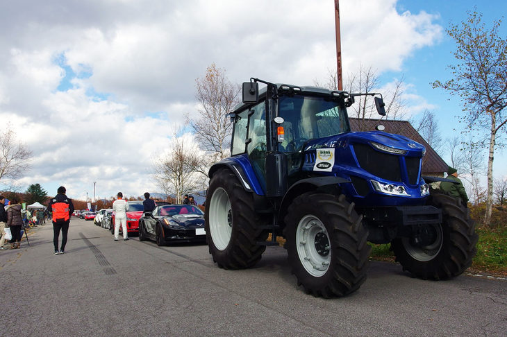 ヒルクライムは午前と午後の2回行われた。写真は2回目の出走に際し、スタート地点へ向かうべく車列を組む参加車両。先導するのは井関農機（ヰセキ）のトラクター「T.Japan W 1233」である。（写真＝webCG）