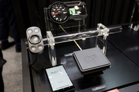 「NS」マーク付きの四角い箱が通信ユニット。さらなるコンパクト化を目指して開発を進めているという。写真左はリモートコントローラー。