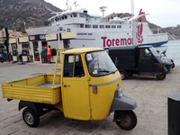 スクーターとともに島の手軽な交通手段はピアッジョ製三輪トラック「アペ」。後方はクルマにも船にも対応している給油所。