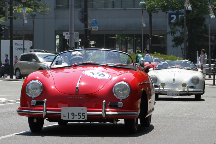 紅白の「ポルシェ356スピードスター」のランデブー。前を行く赤は1955年のいわゆる「プリA」、後ろの白は同じ1955年だが「356A」。プリAから356Aへという、ちょうど切り替わりの時期に該当する2台なのだろう。