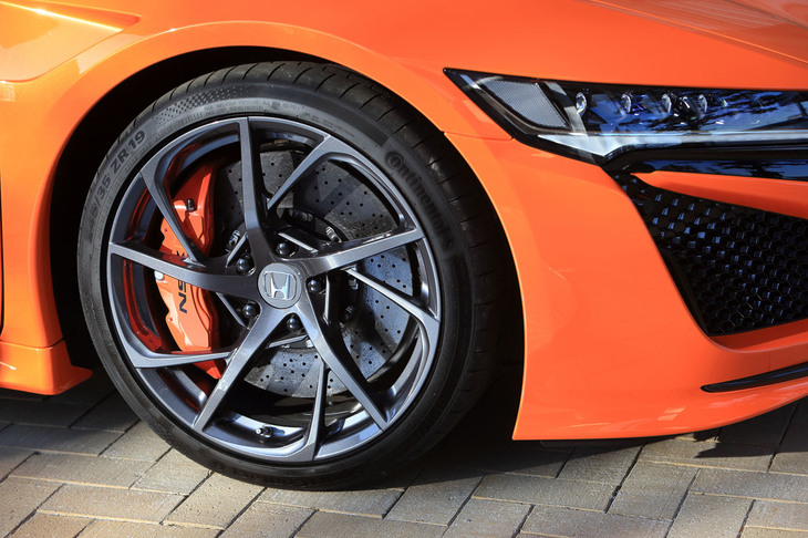 10スポークの「NSX」専用鍛造アルミホイール。タイヤは専用開発の「コンチネンタル・スポーツコンタクト6」が組み合わされている。奥に見えるカーボンセラミックのディスクローターとカラードキャリパーはセットで120万円のオプション。