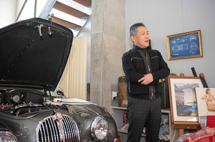 ガレージハウスのオーナー、菅佐原朝幸（すがさわら・ともゆき）さん。傍らのジャガーMk.II 3.8は新車とみまがうばかりのミント・コンディション。