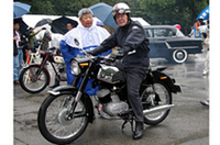 
	2ストローク単気筒エンジンを積んだスズキの「1959年式コレダST-6A」に跨がっているのは、日本人として初めてマン島TTレースに優勝（63年・50ccクラス）した往年の名ライダー、伊藤光夫氏。
	 