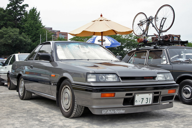 1987年「日産スカイライン 2ドアスポーツクーペ2000GTS-Xツインカム24Vターボ」。ハイソカーブームに合わせて4ドアハードトップ／4ドアセダンだけで登場した“7th”こと7代目スカイライン。不評だったことから、この2ドアスポーツクーペが追加設定された。70km/hを超えるとフロントエアダムから自動的に降りてくるGTオートスポイラーはオプションだった。