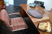 椅子に張られたチェックの生地には、ファイティング・ブルのマークが。机上には伝説のオリベッティ製機械式計算機「スンマ・プリマ20」がある。