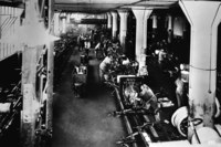 ハイランドパーク工場の組み立てラインの様子（1914年）。ベルトコンベアーを用いた流れ作業の導入により、フォードは過去に例のない自動車の大量生産を実現した。