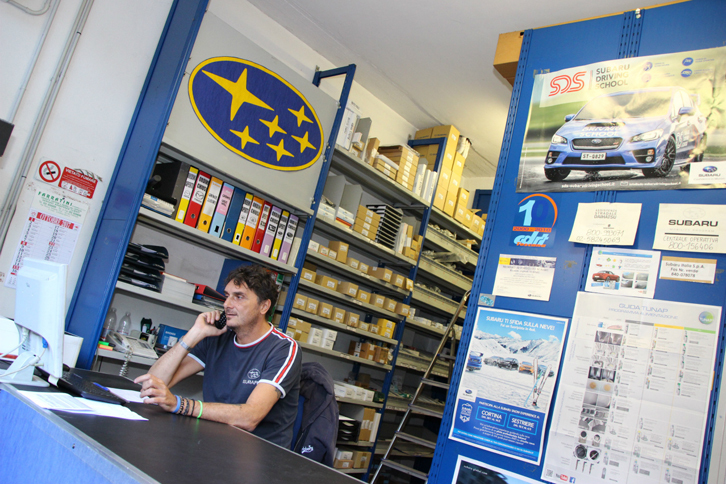 パーツ倉庫と、担当のステファノ氏。頭上の手作り六連星マークが、ブランドへの愛着を感じさせる。