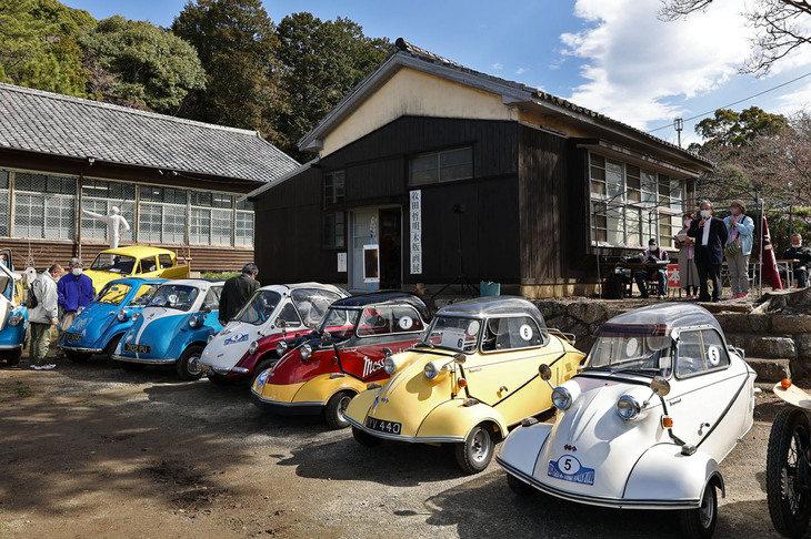 右から3台の「メッサーシュミットKR200」、「トロージャン・ハインケル200」、2台の「BMWイセッタ」といったバブルカー群。アップダウンが多いツーリングコースの走破は難しいということで、サイクルカーとバブルカーは参加しなかった。後方の建物は給食室だったところで、当日はここを会場として豊橋出身の自動車画家・木版画家である牧田哲明さんの作品展も実施された。