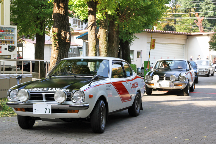 会場入りする参加車両。連れ立ってやってきた2台は、ワークスラリー仕様に仕立てられた型式名A73こと初代「三菱ランサー1600GSR」。