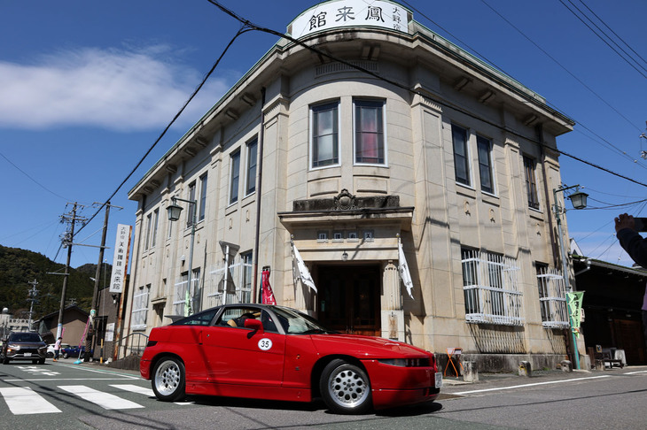 1991年「アルファ・ロメオSZ（ES30）」が通過していくのが大野宿 美術珈琲 鳳来館。これまた登録有形文化財となっている、1925（大正14）年に開業した旧大野銀行本館を使ったカフェ兼ギャラリー。