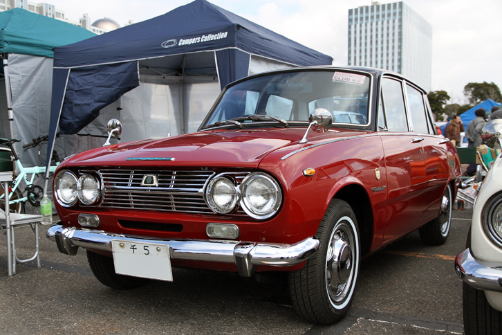 ベレットサルーンクラブのスタンドに展示されていた、新車以来の「千5」ナンバーを付けた1966年「いすゞ・ベレット1500 4ドア デラックス」。ベレットは63年の誕生から10年の間に数えきれないほどの仕様変更を受け、多くの車種追加が行われたが、これは最初に登場した基本形である4ドアセダンの1500デラックス。最初の公式なマイナーチェンジを受ける前の、いわば前期の最終型である。