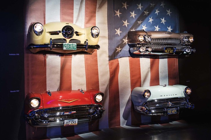 「ダヴィデとゴリア」というスペースタイトルはイタリア人画家、カラヴァッジョの作品名に由来するが、要は巨人（ゴリア）をアメリカ車にたとえ、イタリア車を巨人に戦いを挑んだダヴィデになぞらえているのだろう。まさに巨人だった時代のアメ車がところせましと57台あまり並べられている。星条旗のなかからぬっと顔（フロントマスク）を出す展示方法も楽しい。