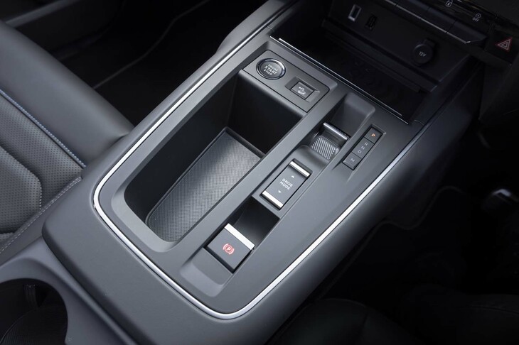 シフトセレクターは背丈のあるレバー式から出っ張りのない高さのトグルスイッチ式に変更。それによって空いたスペースに収納（穴）が用意された。