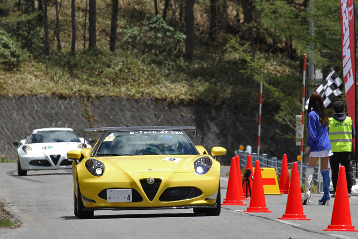 フィニッシュラインではエンドレスレディ（エンドレスのレースクイーン）がチェッカードフラッグを振って迎える。「アルファ・ロメオ4Cスパイダー」と「同4C」が続いてゴールイン。