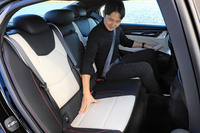 後席の座り心地をチェックするアレック氏。空間効率では不利なFRベースのセダンでありながら、足もとスペースは広々としている。