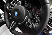 青と赤のステッチで飾られるステアリングホイール。そのスポーク部には、ワンプッシュで走行特性を変えられる“Mボタン”が備わる。