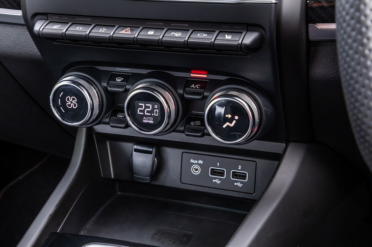 トグルスイッチとダイヤルスイッチ、液晶表示を組み合わせたエアコンの操作パネル。その下にはUSBソケットや12V電源ソケット、スマートフォンワイヤレスチャージャーが機能的に配置されている。