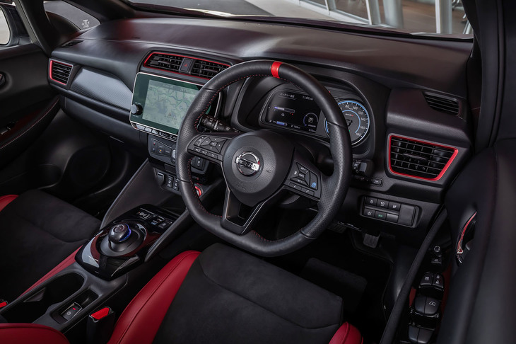 12時の位置にレッドのセンターマークが付く本革のステアリングホイール（写真）はオプションアイテム。エアコン吹き出し口やパワースイッチにあしらわれたレッドの加飾や、ダッシュボードに施されたカーボン調のパネルが「リーフNISMO」のインテリア上の特徴となっている。