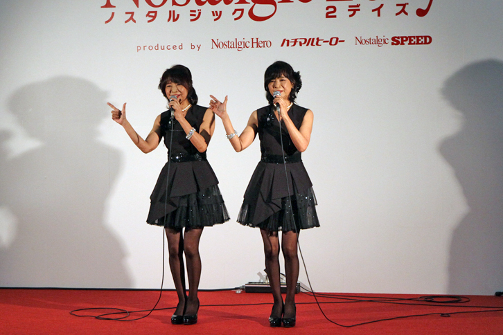 恒例のステージでのライブに、ついにホンモノの（往年の）アイドルが登場。1975年にデビューした双子姉妹デュオの「ザ・リリーズ」である。「デビューは14歳、今は2人合わせて112歳！」と自己紹介しつつ、代表曲の「好きよキャプテン」などを熱唱。昔からスレンダーなボディーだったが、五十路（いそじ）過ぎて、しかも2人そろってこの細さは驚き。