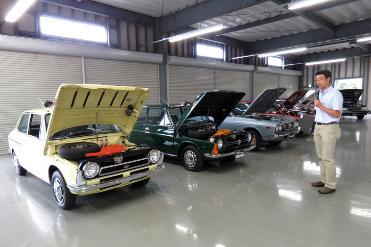 歴代のスバル車を前に、エンジンの進化を語るスバル第二技術本部の小野大輔氏。1966年に登場した「スバル1000」のエンジンには、鉄より14倍も高価だったアルミが使われていた。