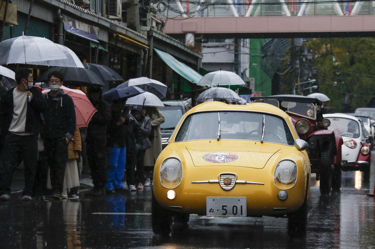 築地の場外市場を抜けていく1957年「フィアット・アバルト750GTザガート」ら参加車両。予期せぬクラシックカーの隊列に観光客もびっくり。