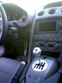 問題の（？）マニュアルギア。ささいなことかもしれないが、アルミで飾られる左足置き場が、ペダル位置に対してドライバーに近すぎるのも気になった点だ。センターコンソールには、ナビゲーションシステムが装備される。その下のスイッチは、向かって右から「右窓」「給油口フタ開閉」「ESPオフ」「ハザード」「フォグ」「ライト」そして「左窓」。エアコンは、左右別々に設定できる。ギアレバーの前あるのは、電動ミラーの調整スイッチ。