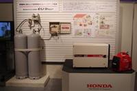 携帯型発電機による、災害時の発電イメージ。家庭用LPガスのボンベ（写真左）から専用ガス供給ボックス（写真中央）を介してLPガスを確保。それを燃料に電気を作り出す。