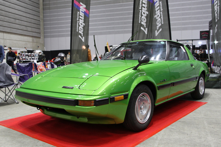 燃料消費が多いことから、石油危機後に評価が落ちたロータリーエンジンを、軽量でコンパクトというメリットを生かしてスポーツカー用ユニットとしてよみがえらせた「マツダ・サバンナRX-7」（SA22C）。1978年のデビュー当時のイメージカラーであるメタリックグリーンをまとったこの個体は、ロータリーエンジンのピストンにあたる、オムスビ型のローターをかたどった純正アルミホイールを履いている。