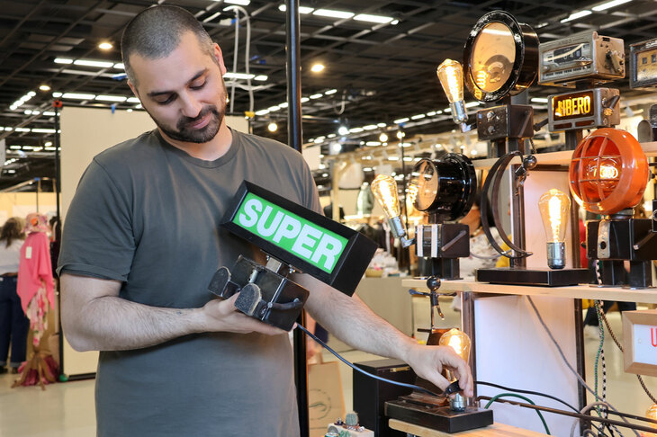 給油機のハイオクガソリン（SUPER）表示を使った照明を、お客に説明するマッテオさん。