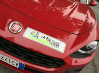 教習所のかわいいオリジナルロゴが貼られた「フィアット124スパイダー」のフロントノーズ。