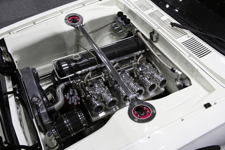 カーボン調のカムカバーやメッキされたソレックスの3連キャブ、ワイヤータック（配管、配線を隠す）風の仕上げなどでクールにキメた通称ハコスカこと「スカイライン2000GT」のエンジンルーム。出展者名は失念した。