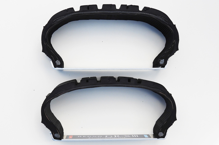 「レグノGR-XII」（上）と「同GR-XIII」（下）の断面。これまではタイヤの変形を均一化するために部材を足していた（ゴムを厚くしていた）が、GR-XIIIではプライ張力分布の最適化により、肉薄なままでも均一な変形を実現。タイヤを軽くしつつ、幅広いシーンで好適な接地面形状、接地圧分布を実現した。