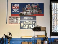 マニェッティ・マレッリの看板と、「お支払いをもって車両を引き渡します。未納の場合は民事法により、車両を保管する権利を有します」の通告。