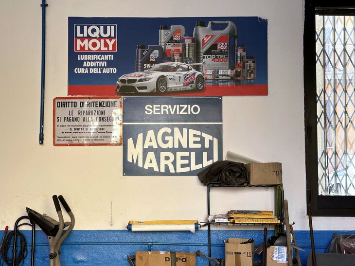 マニェッティ・マレッリの看板と、「お支払いをもって車両を引き渡します。未納の場合は民事法により、車両を保管する権利を有します」の通告。