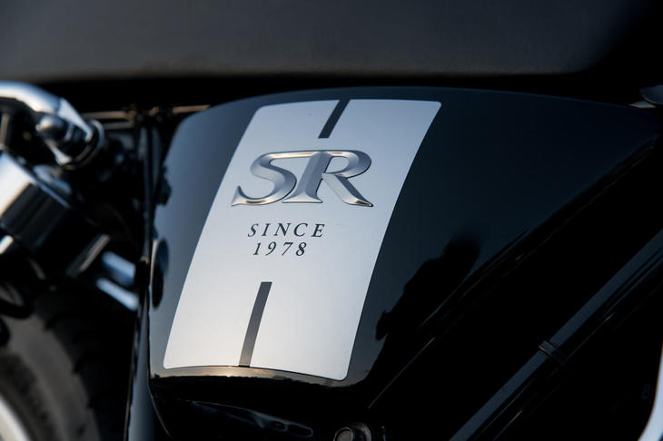 ブラックのモデルのサイドカバーには「SR」の立体エンブレムが添えられる。もうひとつの車体色であるブルーのモデルでは、平面的なデザインの装飾が施される。